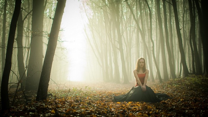 Woman in a red top and dark skirt in a misty forest