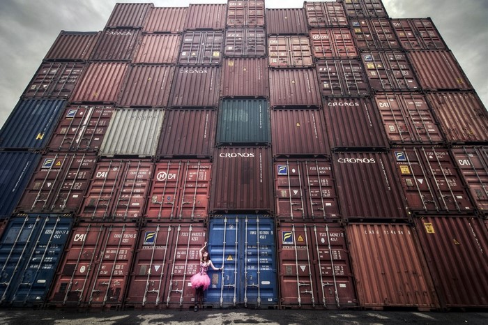 Woman in pink tutu posing in front of stacked shipping containers