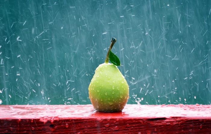Pear Covered in Raindrops on Red Surface