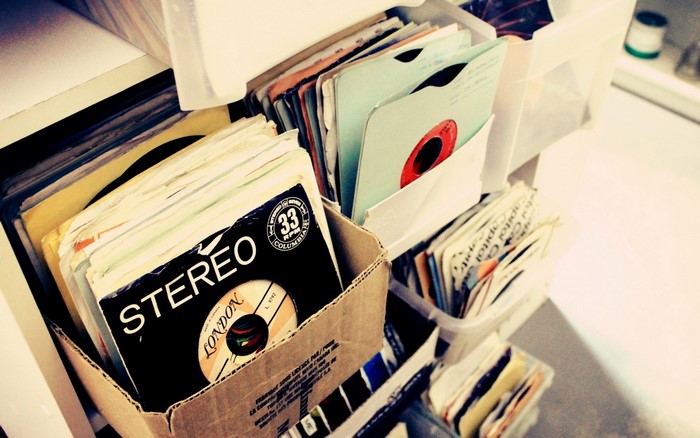 Stack of vinyl records in cardboard box and plastic containers