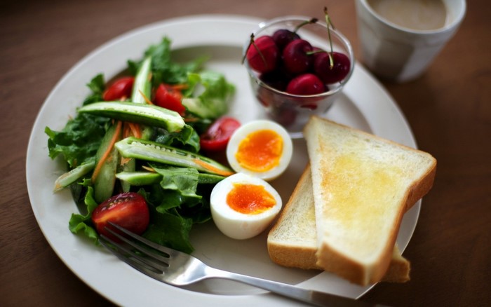 Breakfast plate with salad, eggs, toast, cherries, and coffee