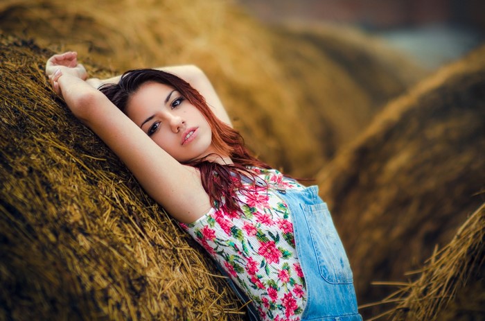 Woman in Floral Top and Overalls Relaxing in Sunlight