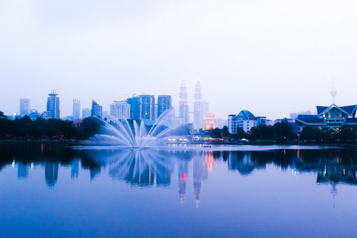 City skyline with fountain and lake reflection at dusk