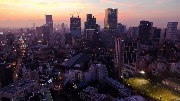 Cityscape at sunset with skyscrapers and a soccer field