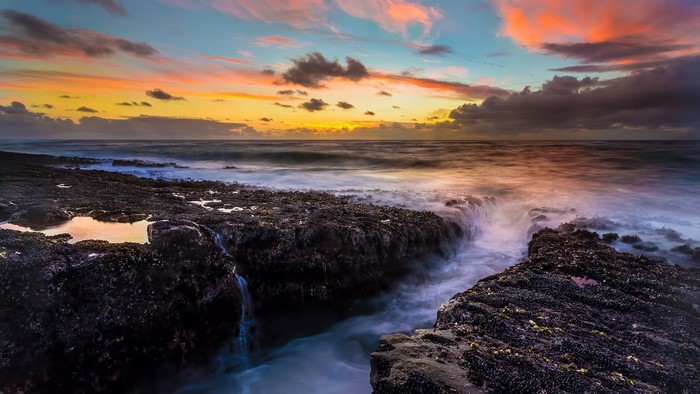 Sunset over rocky coast with ocean waves