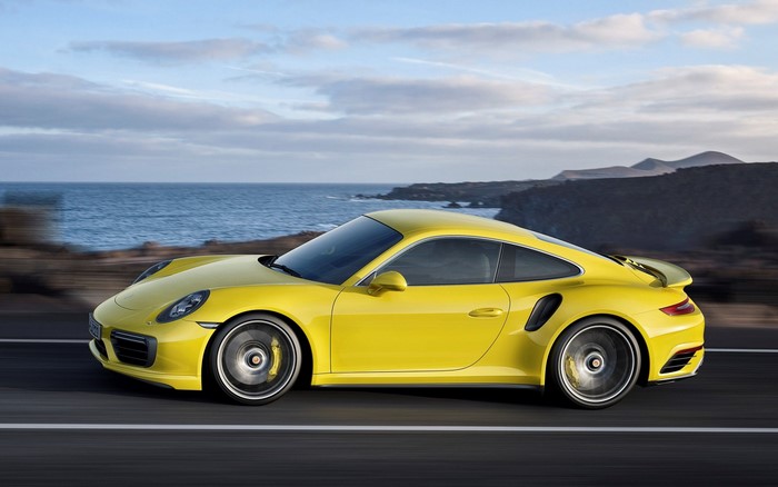 Yellow Porsche 911 Turbo driving on a coastal road