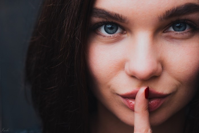 Woman with finger to lips in close-up portrait