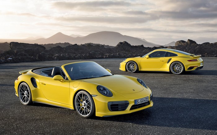 Two yellow Porsche 911 Turbo cars on a road