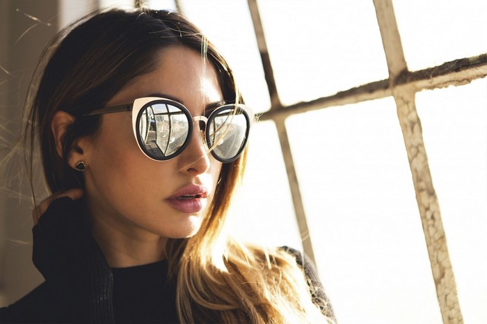 Woman wearing sunglasses by a window