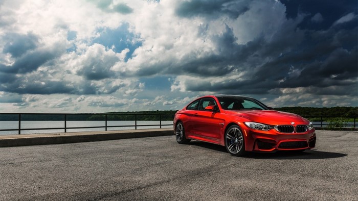 Red BMW M4 Coupe parked by a lake
