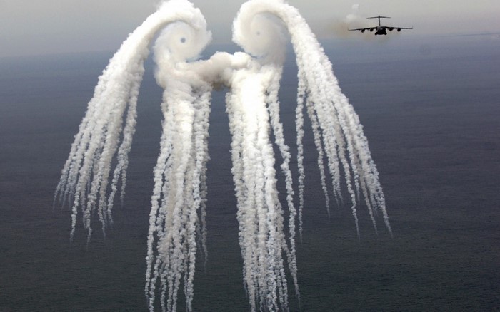 Aircraft releasing smoke trails over the sea