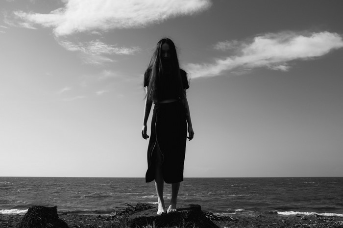 Woman standing on a tree stump by the sea
