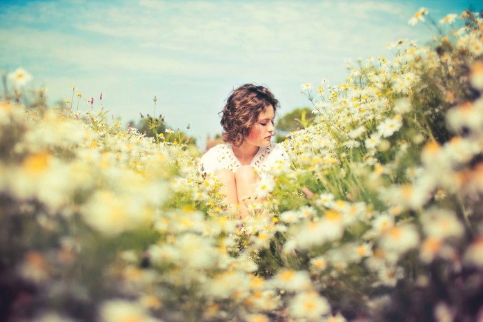 Woman sitting in a field of daisies