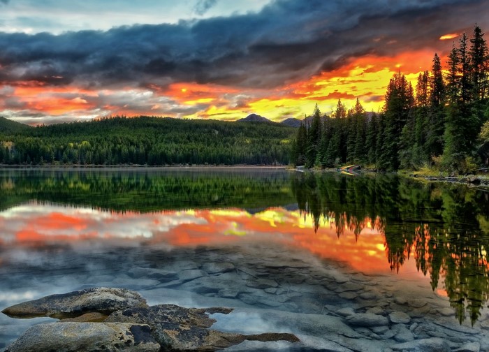 Sunset over a forest lake with rocky shore