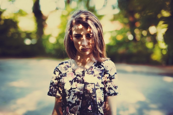 Woman in floral dress with dappled sunlight on face