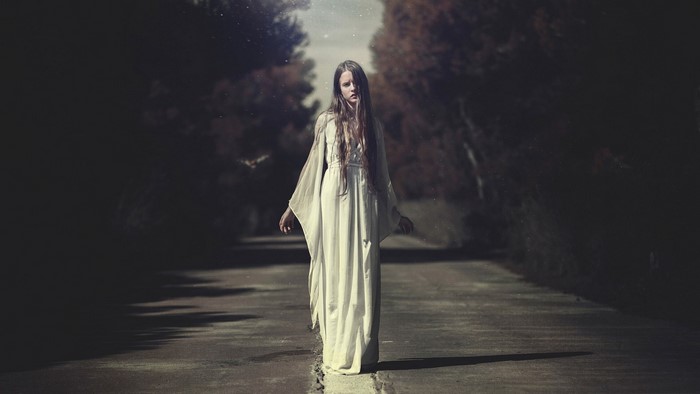 Woman in white dress on a dark road