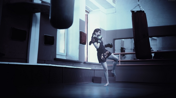 Girl training in a boxing gym with punching bags