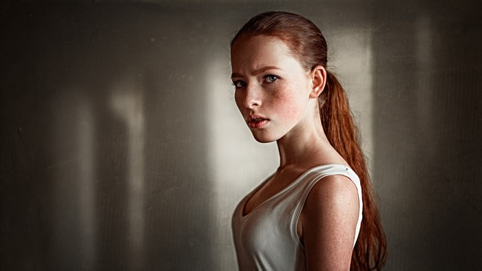 Redhead woman with freckles in a white tank top
