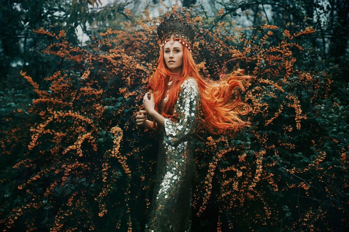 Woman with red hair and crown in a sequined dress