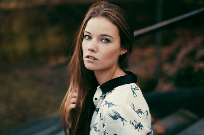 Woman with long brown hair wearing a patterned shirt