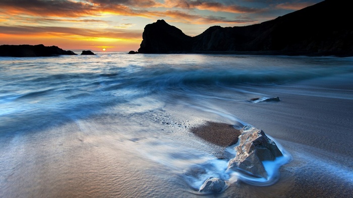 Sunset over a rocky beach with waves