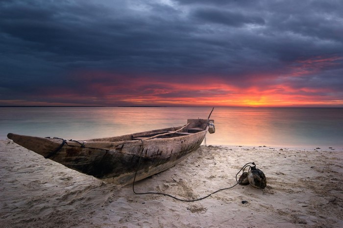 Wooden boat on a sandy shore at sunset