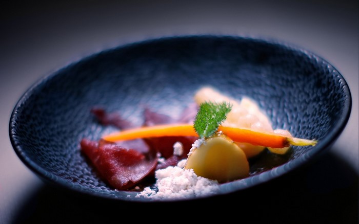 Gourmet dish with beets, carrots, and potato in a dark bowl