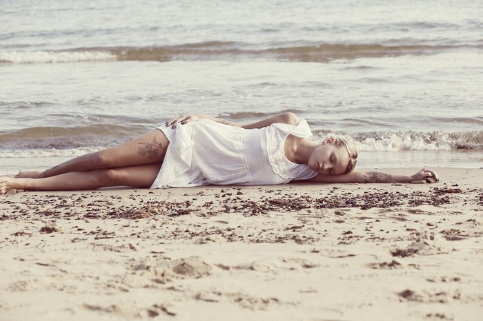 Woman Relaxing on the Beach Shore in White Dress
