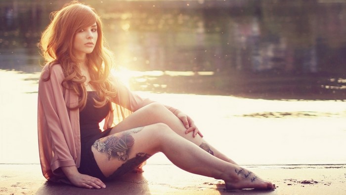 Woman with Long Hair Sitting by Water at Sunset