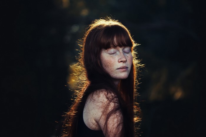 Woman with freckles and red hair in sunlight