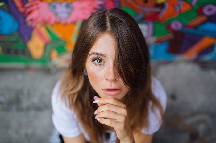 Woman with hand on chin in front of graffiti