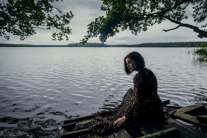 Woman sitting on a wooden dock by a lake