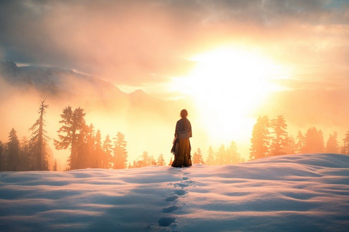 Woman in snow-covered landscape at sunrise