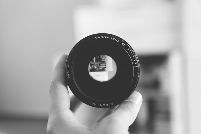 Canon EF 50mm f/1.8 II lens held by a hand
