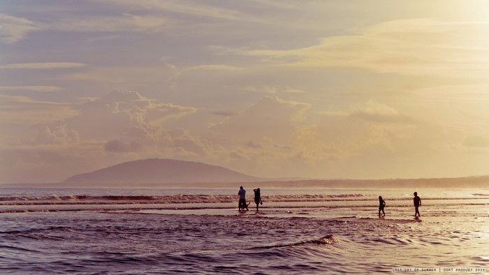 People walking on a beach at sunset