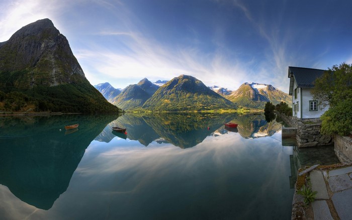 Panoramic view of a Norwegian fjord with mountains and a house