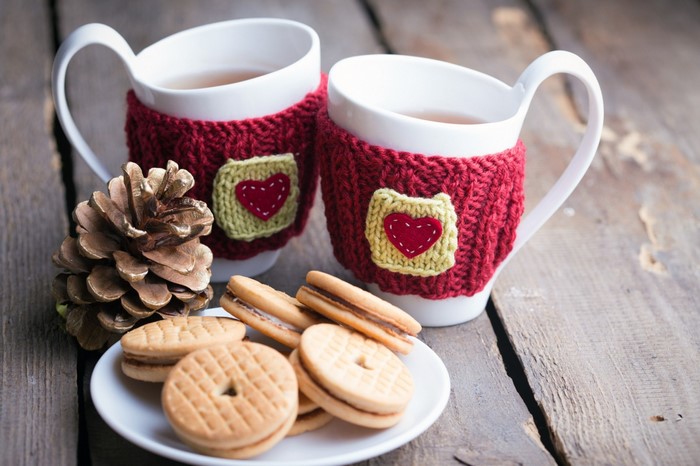 Two cups of tea with cookies and pine cone