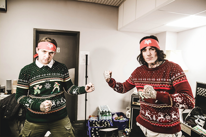 Two men in Christmas sweaters and bandanas