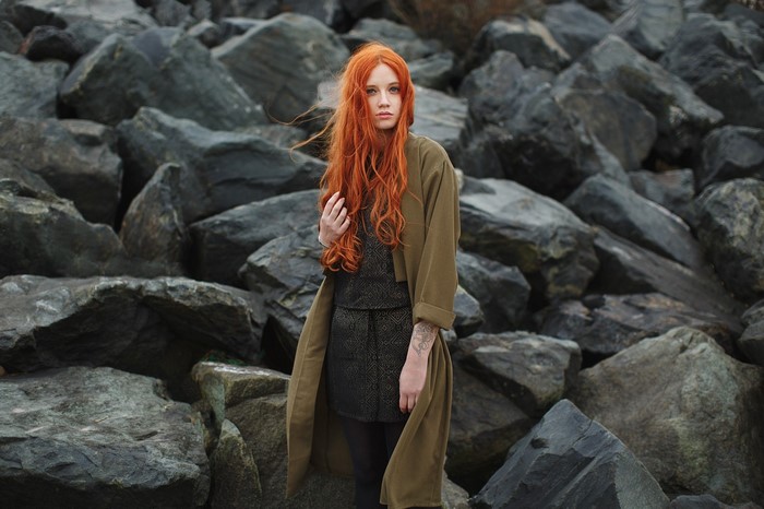 Redhead woman with tattoo standing on rocks