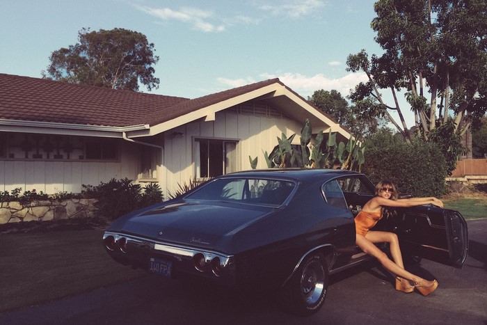 Woman in swimsuit leaning on vintage car