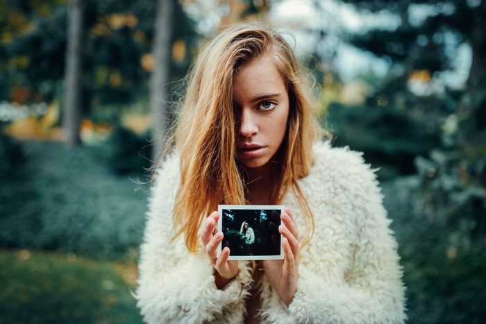Woman holding a photo in a forest