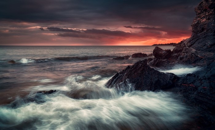 Ocean waves crashing on rocky shore at sunset
