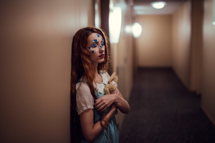 Woman with eyes painted on face holding stuffed rabbit