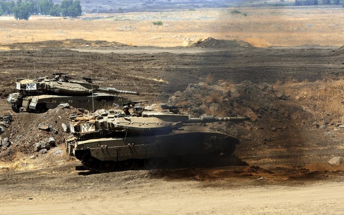Merkava Mark IV tanks in a dusty, arid landscape