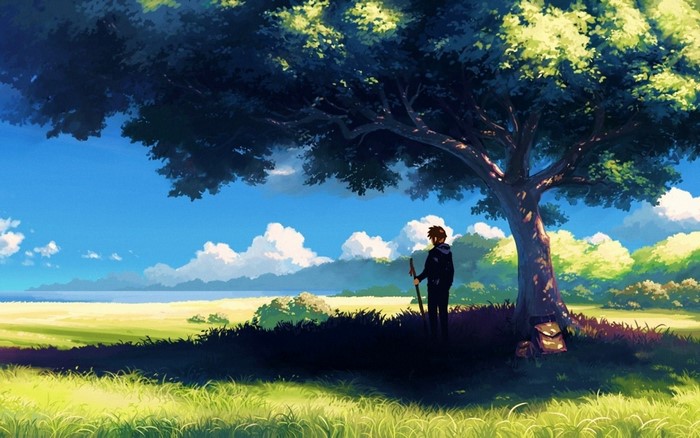 Boy with staff under a tree in a sunny field
