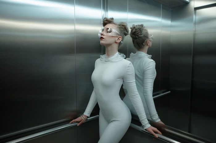 Woman in White Catsuit Posing in Elevator