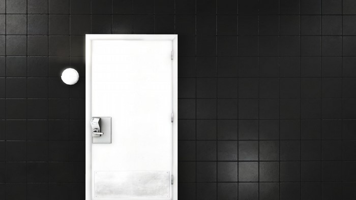 White door with silver handle on black tiled wall
