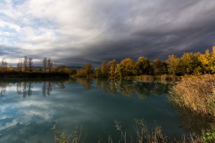 Autumn lake with trees and dramatic clouds