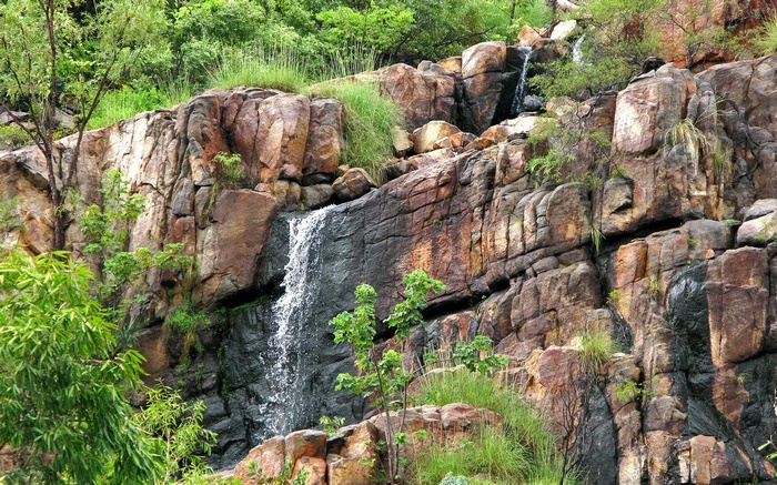 Waterfall cascading over rocky cliff face with greenery