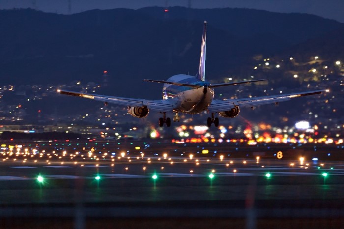 Airplane landing at an airport at night with city lights